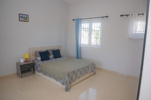 A bedroom with a bed, nightstand, lamp, window with curtains, and a wall-mounted picture. - No. 17 - The Grand Gaube Retreat – Pool, Turquoise Sea Just Steps Away (Grand Gaube)