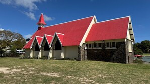 A building with a red roof and stone walls, surrounded by a grassy area. - No. 17 - The Grand Gaube Retreat – Pool, Turquoise Sea Just Steps Away (Grand Gaube)