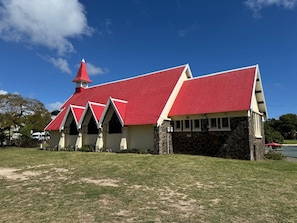 A building with a red roof and stone walls, surrounded by a grassy area. - No. 17 - The Grand Gaube Retreat – Pool, Turquoise Sea Just Steps Away (Grand Gaube)