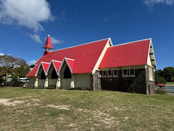 Un edificio de paredes de piedra y techo rojo, rodeado de césped.