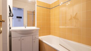 A bathroom with a white sink, a bathtub, and yellow-tiled walls. - Classic Riviera Escape With Pool, Grasse (Grasse)