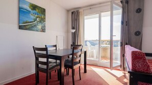 A dining area with a table and chairs, a painting on the wall, and a balcony with a view. - Classic Riviera Escape With Pool, Grasse (Grasse)