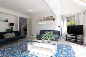 Una sala de estar moderna con sofá, televisión, mesa de centro y una escalera.