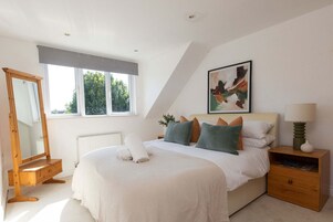 Un dormitorio con una cama grande, una mesita de noche, un espejo y una ventana.