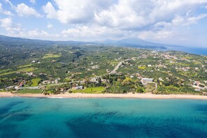 An aerial view of a coastal town with a beach, green hills, and scattered buildings. - Angira 5 Seaview Escape - Koroni Bright Getaway (Pylos-Nestoras)