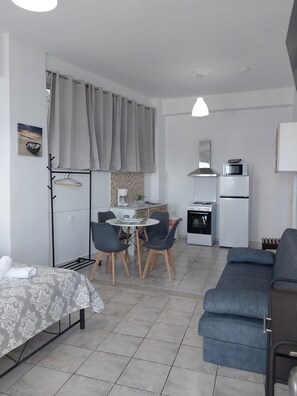 A compact living space with a kitchenette, a dining area with chairs, a sofa, and a bed. - Angira 2 Seaview Escape - Koroni Comfy Getaway (Pylos-Nestoras)