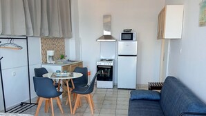 Kompakti oleskelutila, jossa on pieni keittiönurkkaus, ruokailualue ja sohva.
