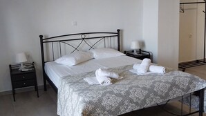 A neatly made bed with a patterned bedspread, two bedside tables with lamps, and a hanging light fixture. - Angira 4 Seaview Escape - Koroni Summer Getaway (Pylos-Nestoras)