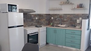 A modern kitchen with white appliances, teal cabinets, and a dining area with a table and chairs. - Angira 4 Seaview Escape - Koroni Summer Getaway (Pylos-Nestoras)
