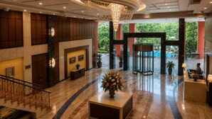 A spacious lobby with a grand chandelier, a reception desk, and a staircase leading to an upper level. - Bel La Monde Blu Chhattarpur (New Delhi)