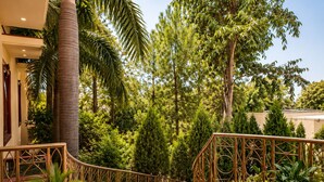 A red-tiled outdoor staircase with ornate metal railings, surrounded by lush greenery and tall trees. - Bel La Monde Blu Chhattarpur (New Delhi)