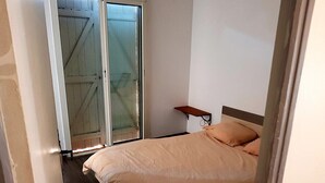 Ein Schlafzimmer mit Bett, Nachttisch, Fenster und Tür.