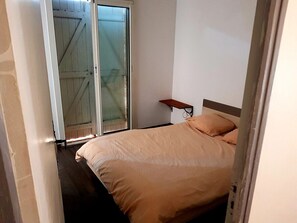 Ein Schlafzimmer mit Bett, Nachttisch, Fenster und Tür.