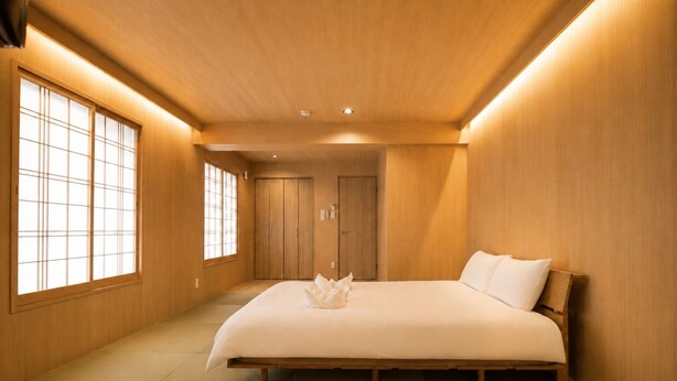 Ein schlicht eingerichtetes Schlafzimmer mit einem großen Bett, Schiebetüren und Holzboden.