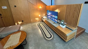 Un salon moderne avec un téléviseur, des murs recouverts de panneaux en bois, un canapé et un lampadaire.