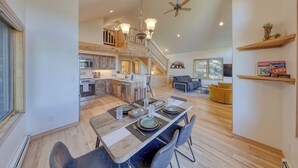 Une cuisine spacieuse avec un coin repas, un escalier en bois et un ventilateur de plafond.
