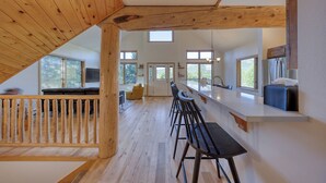 Une cuisine moderne avec des poutres en bois, un coin bar et de grandes fenêtres.