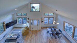 Un loft spacieux avec de hauts plafonds, de grandes fenêtres, un coin repas et un espace salon confortable.