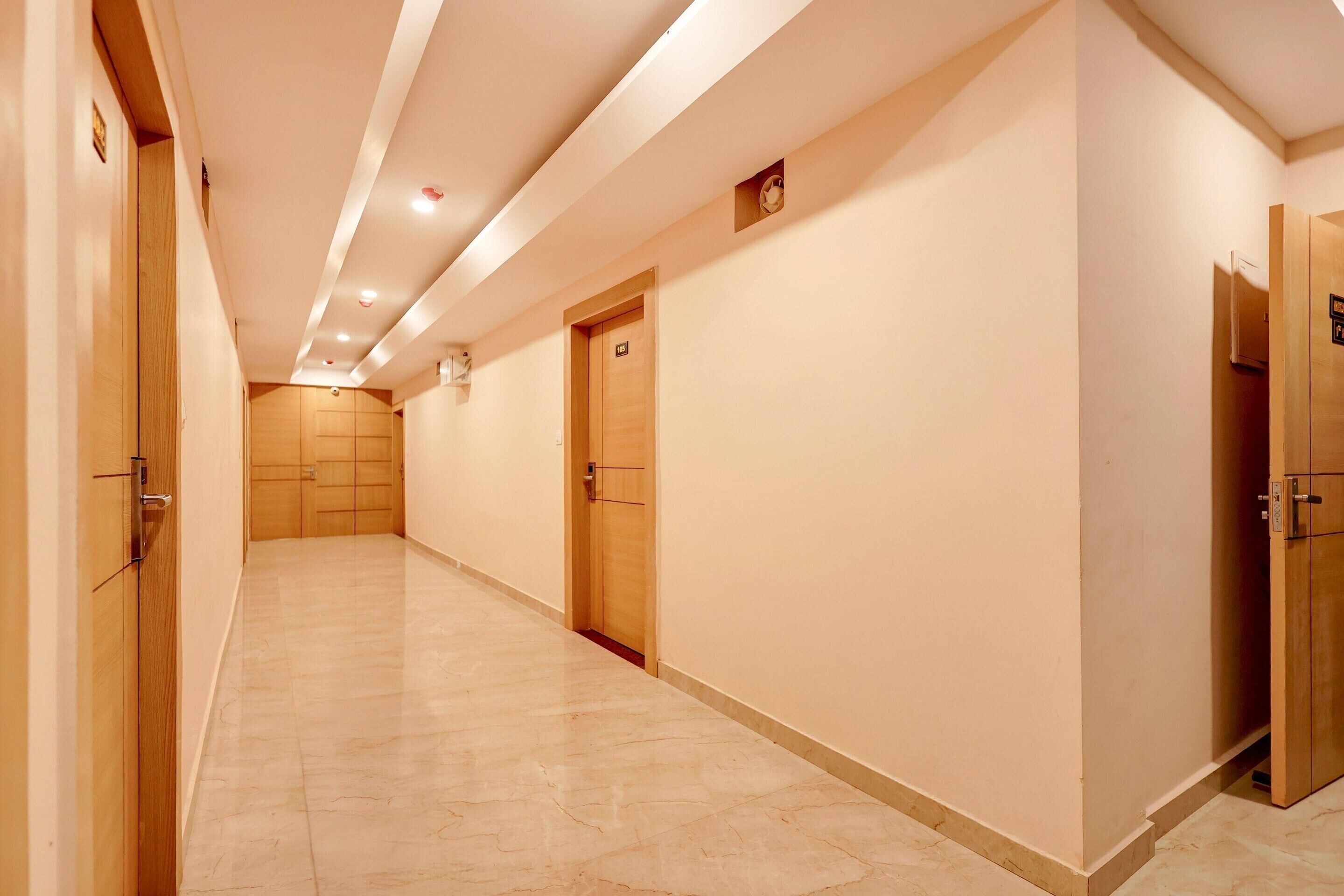 A corridor with wooden doors, a tiled floor, and recessed lighting.