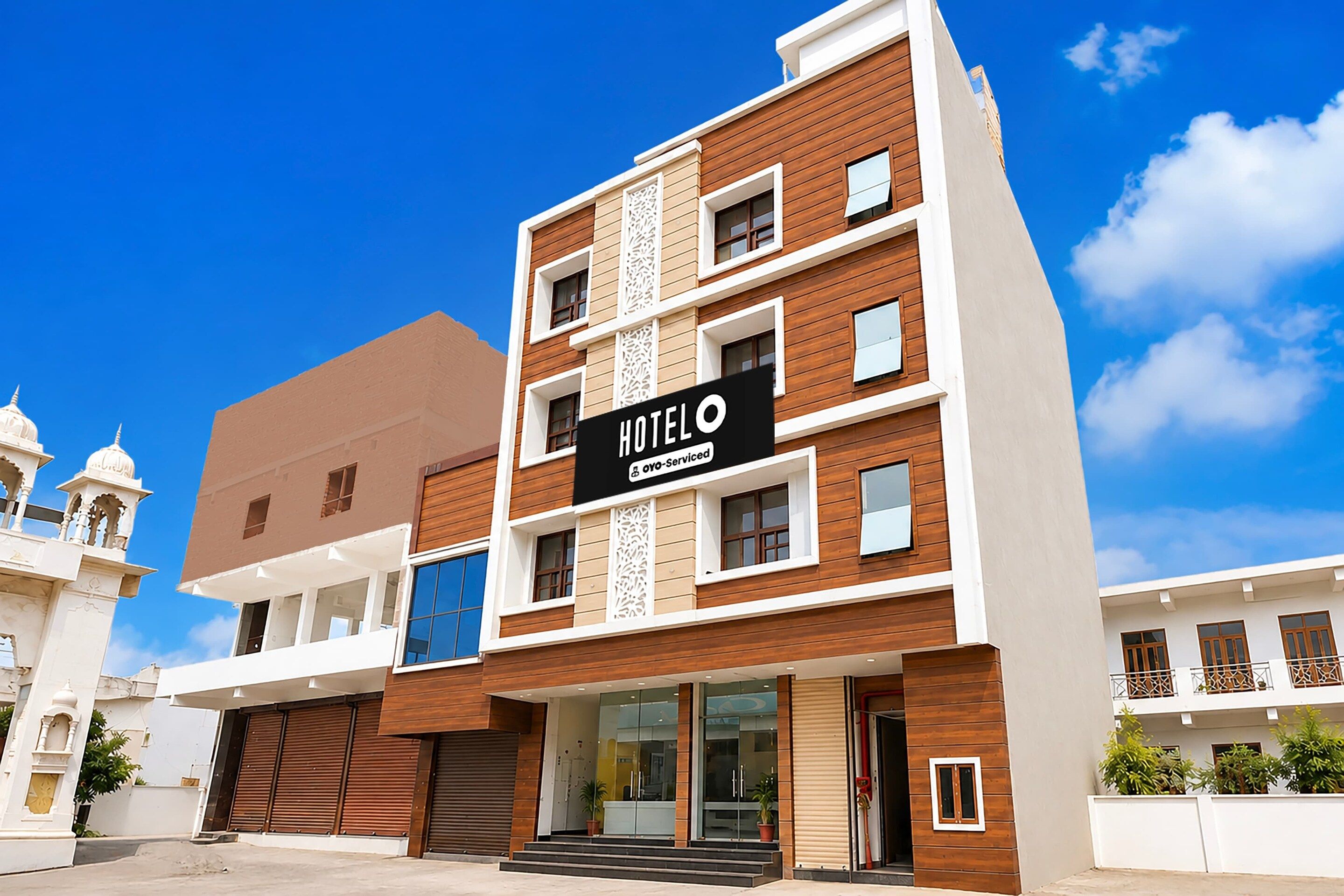 A multi-story hotel with a modern facade, featuring a prominent sign for 'HOTEL OYO-SERVICED'.
