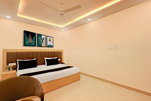 A hotel room with a bed, a nightstand, a chair, and artwork on the wall.