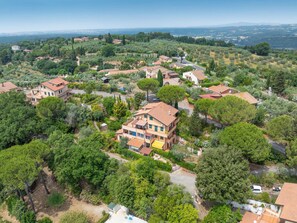 An aerial view of a residential area with houses surrounded by greenery, roads, and distant hills. - Rio del sole by Interhome (Montescudaio)