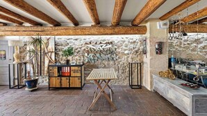 A rustic interior with exposed wooden beams, a stone wall, a wooden cabinet with numbered drawers, a folding table, and a bench with a motorcycle.