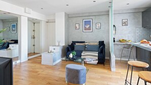 Una sala de estar moderna con un sofá, una mesa de centro y una zona de cocina con mostrador y taburetes.