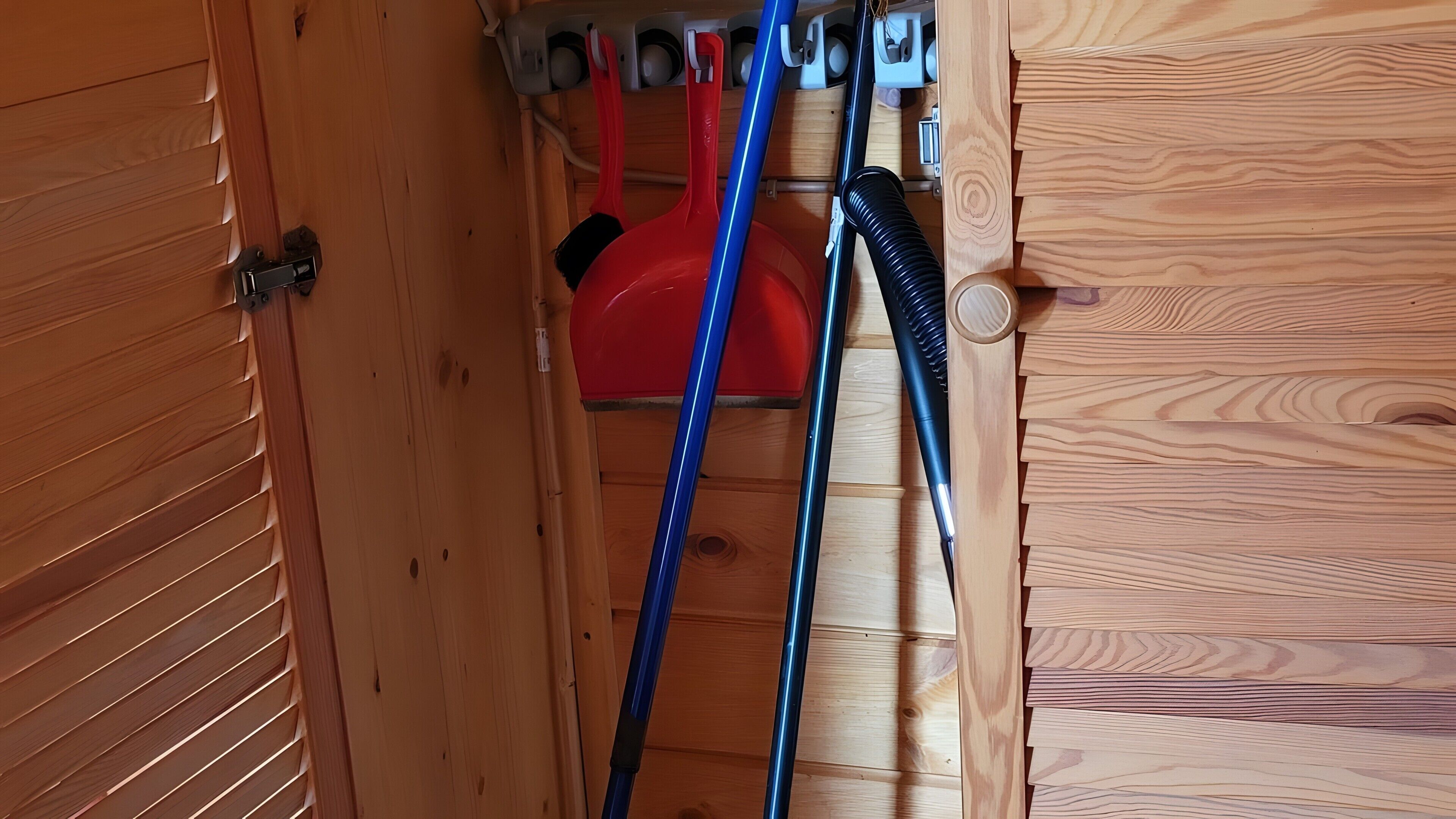 A wooden interior with a door, a red object, and a blue hose.