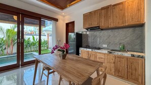 Una cocina moderna con armarios de madera, encimera de mármol y vistas a un jardín tropical.