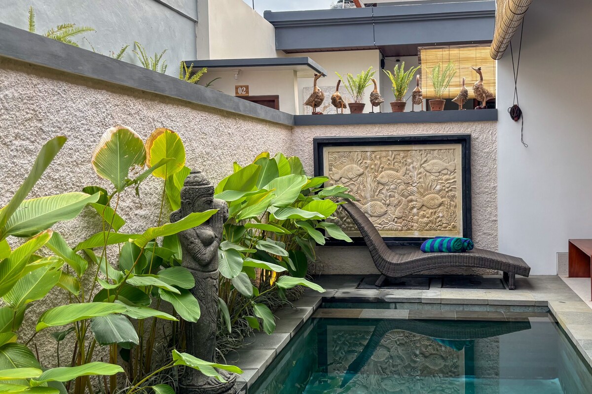 A pool area with a lounge chair, potted plants, and a decorative wall.