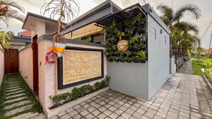 Una casa moderna con un relieve decorativo de peces, un jardín pequeño y un letrero que dice 'PADI MAS VILLE'.