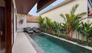 A pool area with lounge chairs, a small pool, and tropical plants. - Padi Mas Villas with Private Pool (Bali)
