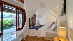 Un dormitorio con cama a dosel, lámpara de noche y vistas a una piscina y follaje.