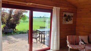 Una cabaña de madera con un ventanal de vidrio que da a un patio exterior con una mesa y sillas.