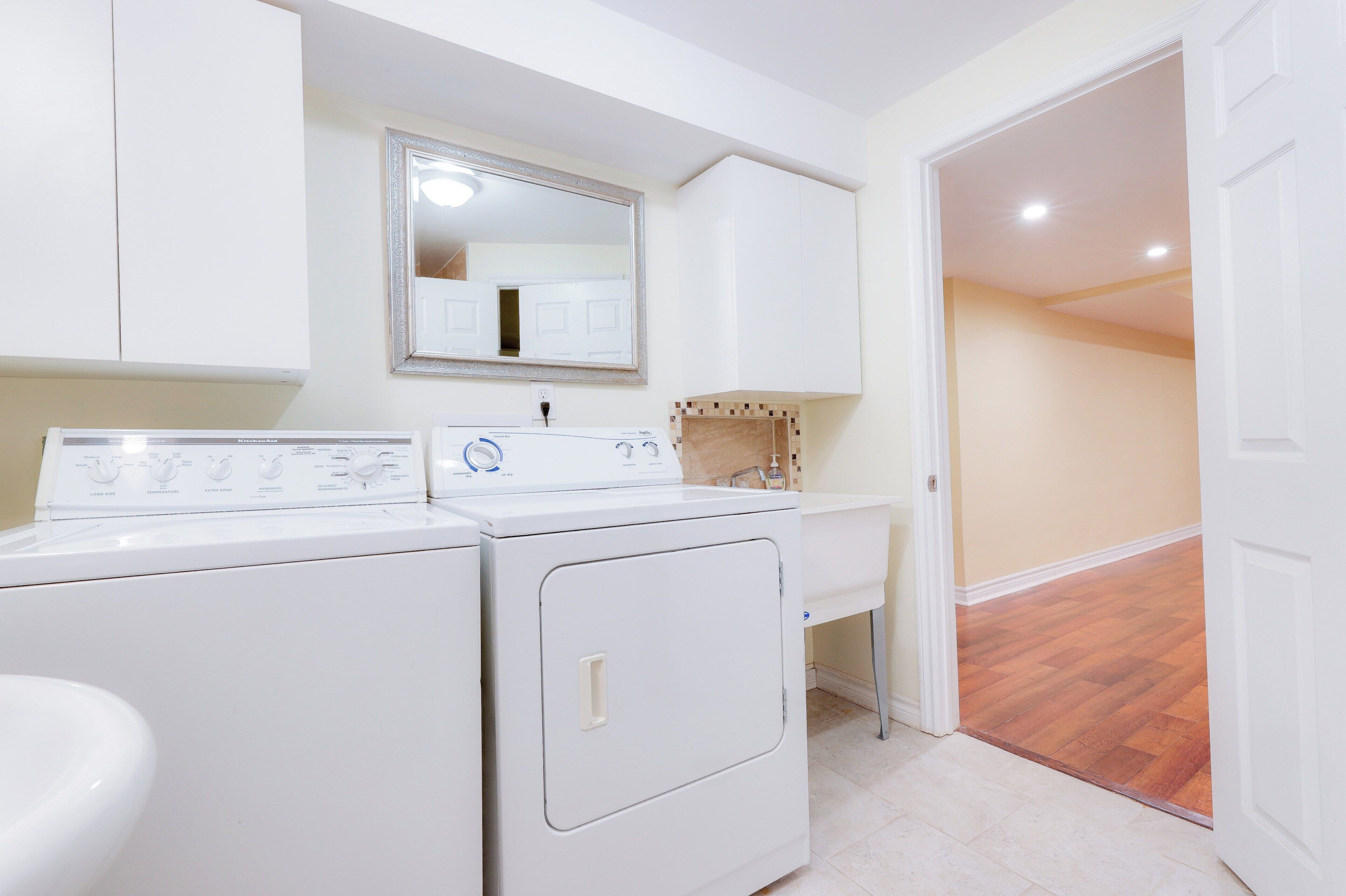 A laundry area with a washing machine, dryer, and a mirror above a sink.