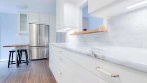 A modern kitchen with white cabinetry, a stainless steel refrigerator, and a marble countertop. - Stylish Home near Luxury Spa & GO Station (Whitby)