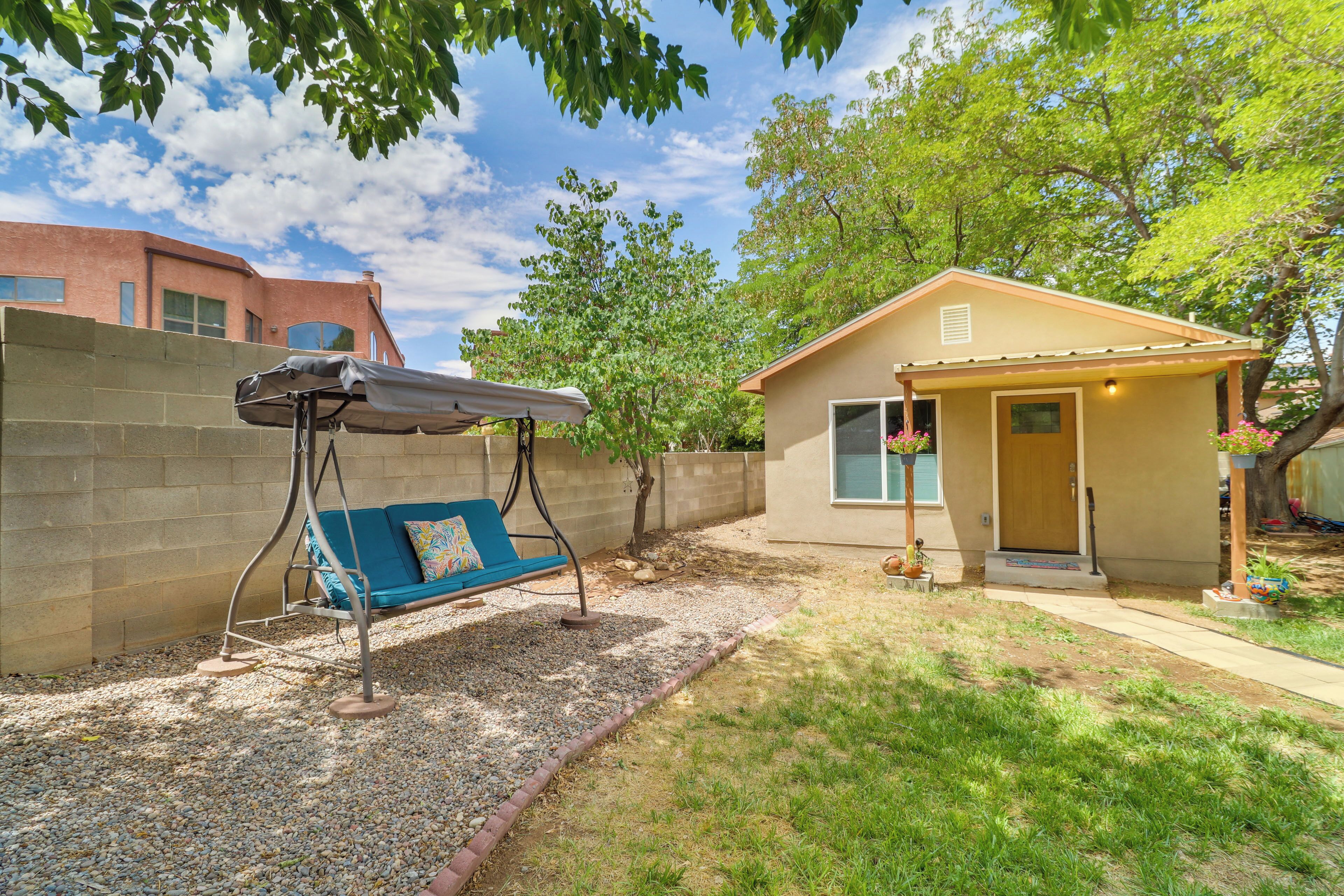 A small house with a porch, a swing, and a gravel area.