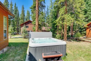 Ein Whirlpool in einem bewaldeten Garten mit einer Holzhütte im Hintergrund.
