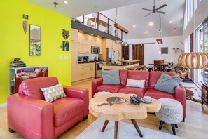 Ein modernes Wohnzimmer mit einem roten Sofa, einem Holztisch und einer Küche im Hintergrund.