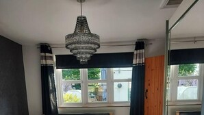 Un dormitorio con cama, espejo, ventana y candelabro.
