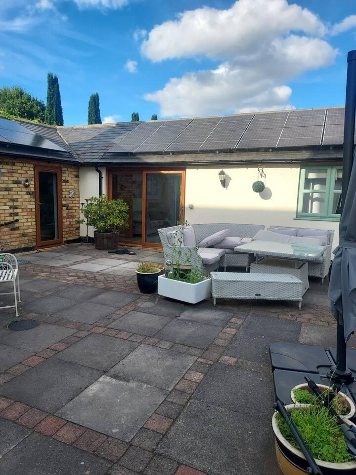 A patio area with outdoor furniture, a brick wall, and a solar panel roof.