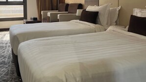 Ein Hotelzimmer mit zwei Betten, einem großen Fenster, einer Kopfteil und einem Teppichboden.