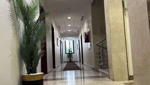 Ein Hotelgang mit Marmorboden, Blumentöpfen und einem Notausgangsschild.