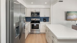 A modern kitchen with stainless steel appliances, white cabinetry, and a marble countertop. - Remodeled Spacious 3bd Across From Beach I Koa Resort 2H (Kihei)