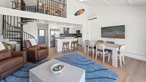 A spacious living area with a staircase, a dining set, and a kitchen in the background. - Remodeled Spacious 3bd Across From Beach I Koa Resort 2H (Kihei)