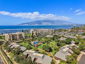 A coastal resort with multiple buildings, a swimming pool, and a view of the ocean and mountains. - Remodeled Spacious 3bd Across From Beach I Koa Resort 2H (Kihei)