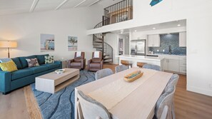 A modern living space with a dining area, a sofa, a coffee table, and a staircase leading to an upper level. - Remodeled Spacious 3bd Across From Beach I Koa Resort 2H (Kihei)