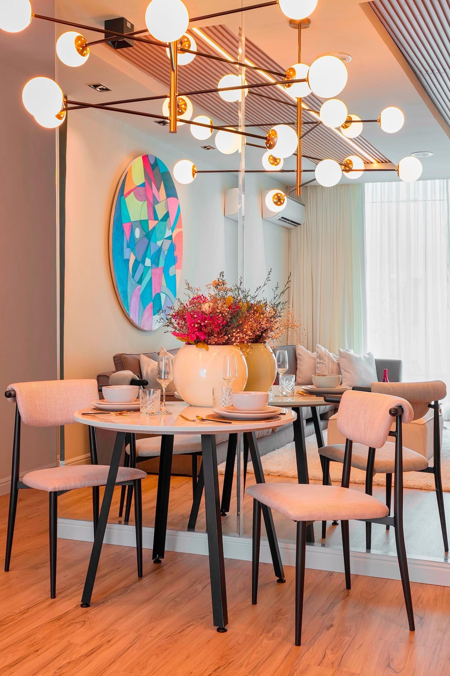 A dining area with round tables, chairs, a vase with flowers, and a colorful abstract painting on the wall.