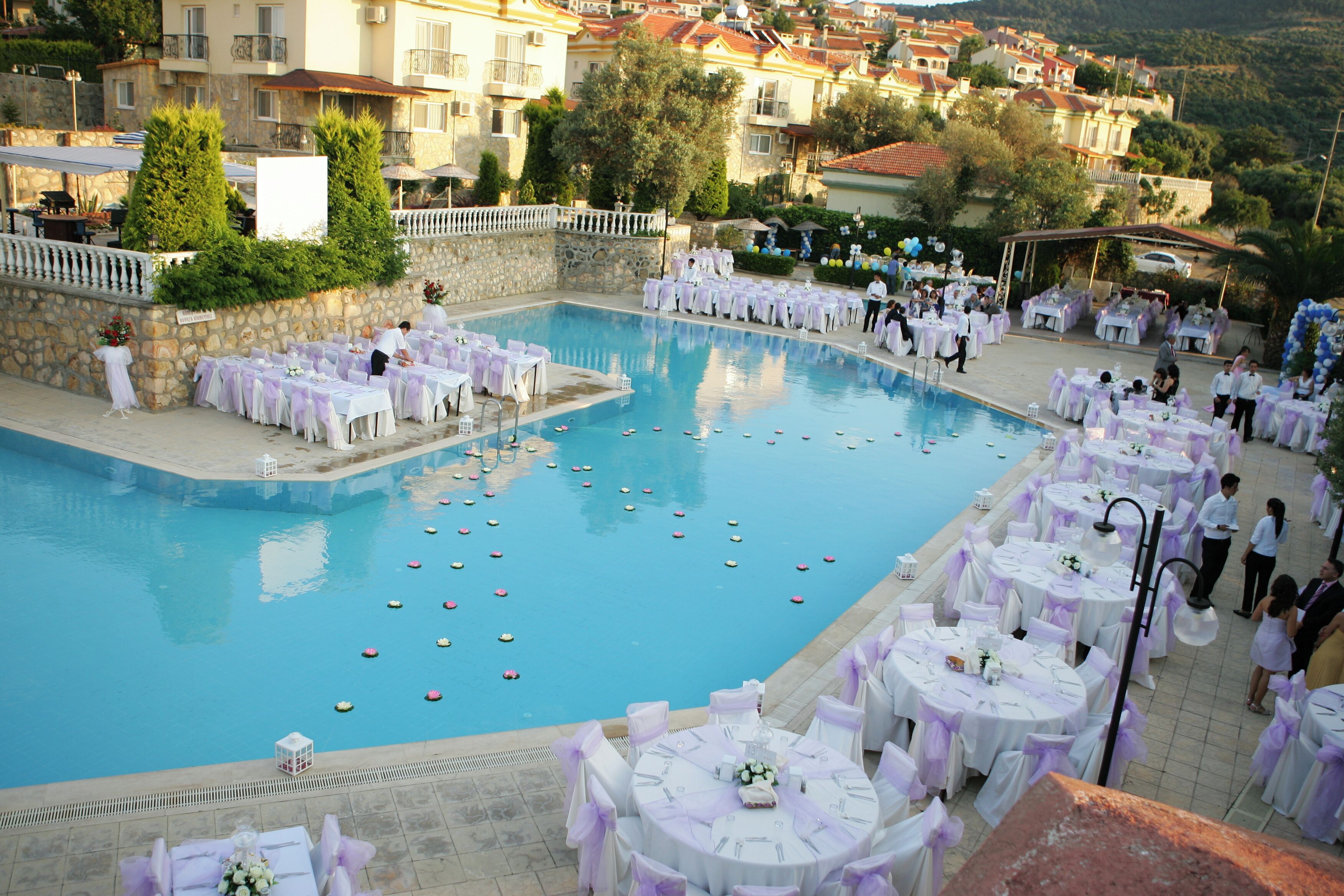 Evento junto a la piscina con mesas y sillas dispuestas para los invitados.